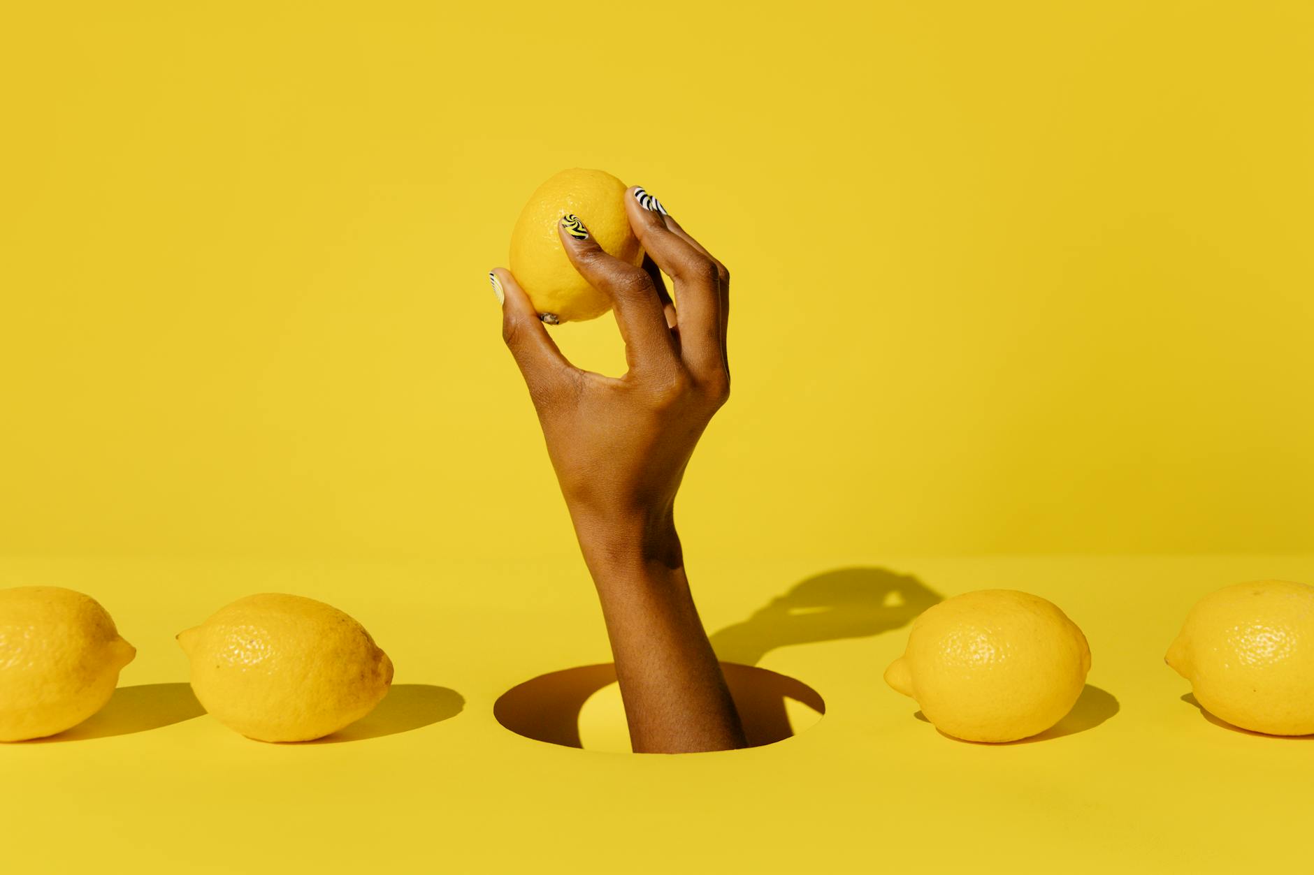 Close-up of hands holding a sleek lemon clitoral vibrator