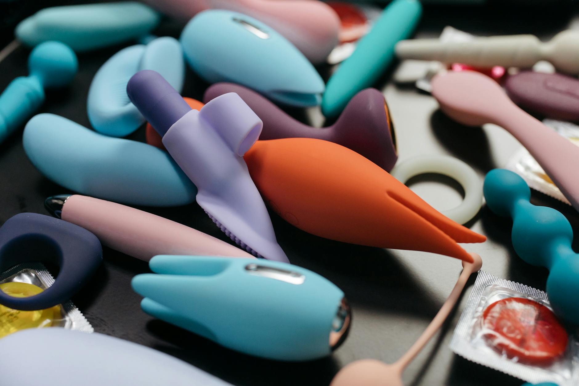 A hand holding an orange vibrator against a purple backdrop, symbolizing pleasure and recovery.